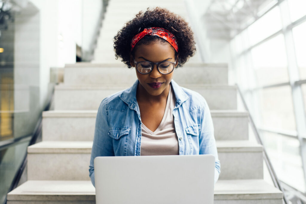 Woman-with-glasses-sitting-on-stairs-at-computer-focus-and-productivity