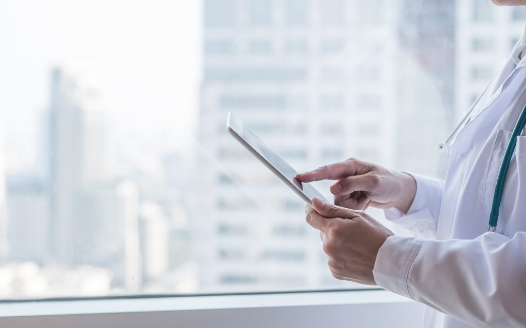 functional-medicine-doctor-standing-by-the-window-with-tablet